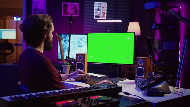 Music producer learning to use mixing console and soundboard, using online tutorial lesson on greenscreen. Artist learns to edit songs and add audio effects, mixing and mastering tracks. Camera B.