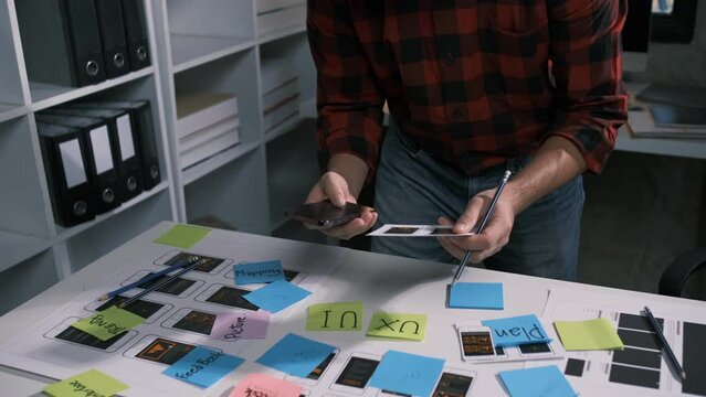 An employee is planning an event in a conference room with documents scattered across the table before preparing to present it in front of his co-workers and boss.