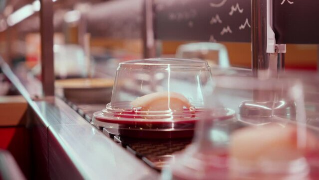 Conveyor belt sushi close-up with covered dishes in a restaurant