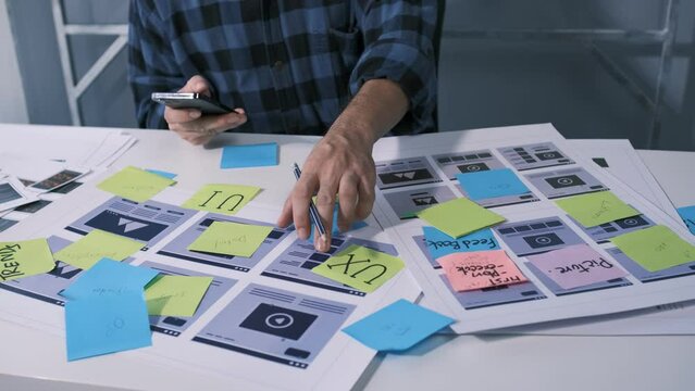 An employee is planning an event in a conference room with documents scattered across the table before preparing to present it in front of his co-workers and boss.