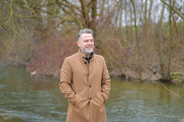 Middle aged man in a park in winter or spring with his hands in pockets