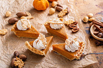 Fototapeta na wymiar Festive pumpkin pie slices decorated with whipped cream