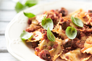 Ravioli with mushrooms and fresh basil. Bright wooden background. Close up.	