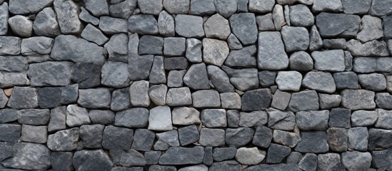 A detailed view of a grey stone wall showcasing the intricate pattern of the brickwork. The natural...