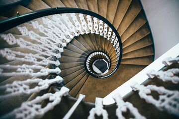Looking down from the top of an elegant spiral staircase with a black railing