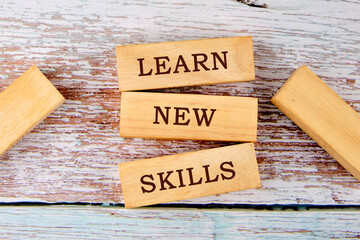 LEARN NEW SKILLS symbol on wooden blocks on old boards. Business concept