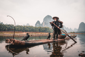 Cormorant fisherman and his birds on the Li River in Yangshuo, Guangxi, China.