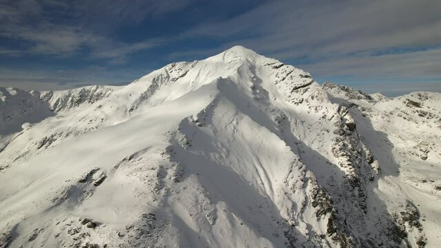 Lespezi peak in fagaras mountains under a clear blue sky, snowy landscape, aerial view