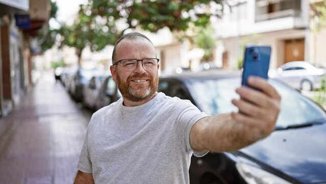 Caucasian man smiling confident making selfie by the smartphone at street