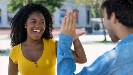 Beautiful african american female young adult giving high five to hispanic friend