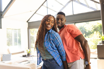 A young African American couple dancing together and smiling at home