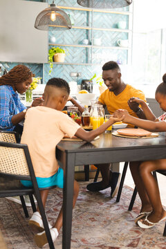 An African American family saying grace and praying before breakfast together at home