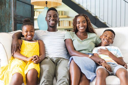A cheerful African American family is sitting closely on a sofa at home