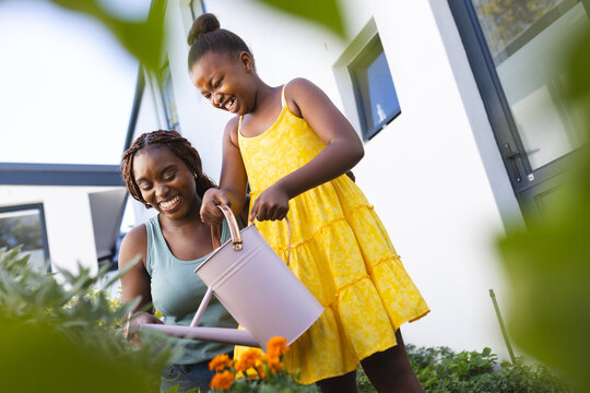 A young African American mother and her daughter are gardening together at home