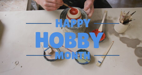Image of happy hobby month text over caucasian man painting pottery