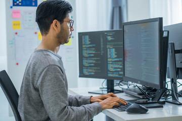 Asian prompt engineer developer coding app with software data sitting in front of computer monitor at office - 758622426