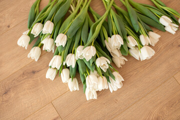 White tulips lying flat on a wooden floor.