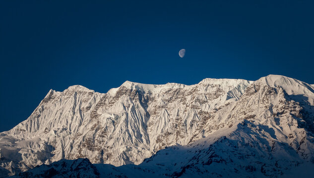 Snow-capped mountains of Tibet at sunrise and moon in the sky