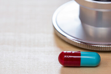 Close up pills and stethoscope on wooden table