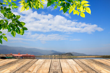 Green leaves and wooden table with blured blue sky background