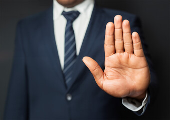 Businessman in suit showing stop gesture with his hand, closeup