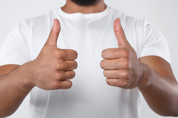Close-up of african american man showing thumbs up on white background