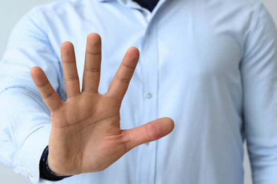 Businessman showing stop gesture on light background, closeup of hand