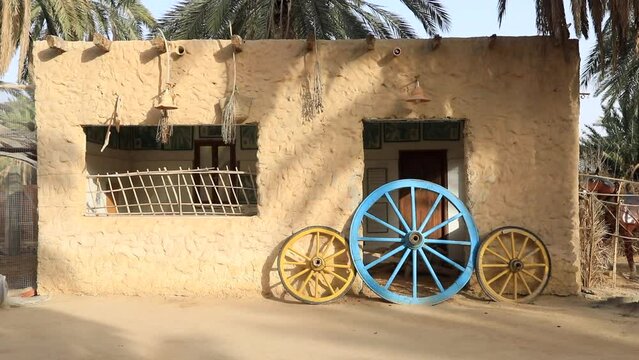 Brightly painted wheels against an ancient mud brick house in Sbeitla, daylight