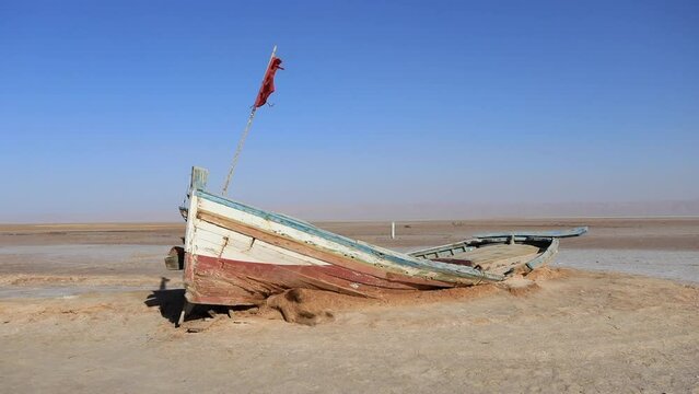 Abandoned boat on the salt flats of Chott el Jerid, Tunisia under a clear blue sky