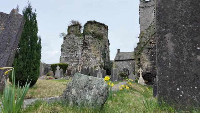Old Irish graveyard with castle and headstones in spring