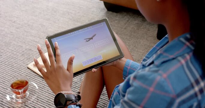 A young African American woman is browsing a travel booking site on her tablet