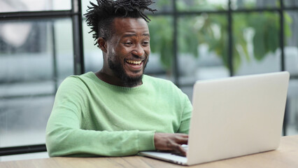 Close-up of a laughing african american man looking into a laptop