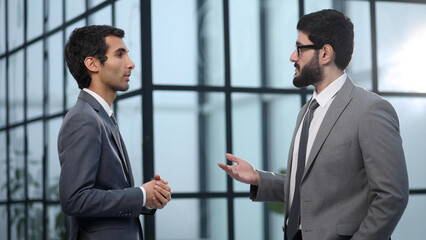 Two businessmen discussing project at meeting at office.