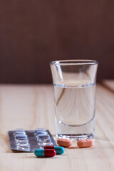 pills and tablets with glass water on wooden table