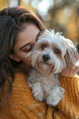 Close-up portrait of young beautiful girl hugging and kissing her cute dog while walking in autumn park. Love and affection between owner and pet.