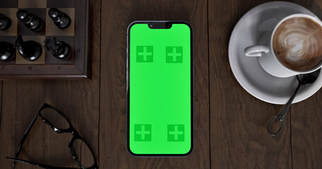 Smartphone place on coffee table, Green screen cellphone, Close up display mobile phone with mock...