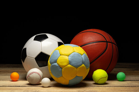Set of various sport balls on wooden floor on black background © fotofabrika