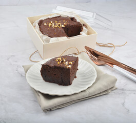 premium freshly baked dark cocoa chocolate brownie gold flower and earl grey peanut round birthday cake with walnut in wood bento box on white marble halal food sweet dessert menu for pastry cafe shop