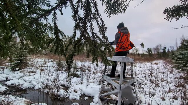 Wildlife hunter at a watch tower, waiting for prey, in a snowy forest, winter day