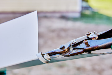 Sheet metal cutters, spring loaded with lock hook, builder cuts edge of steel sheet of an external...