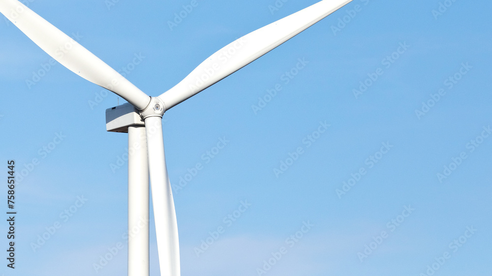 Wall mural close-up color photo of large wind turbine blades against a blue sky background with copy space.