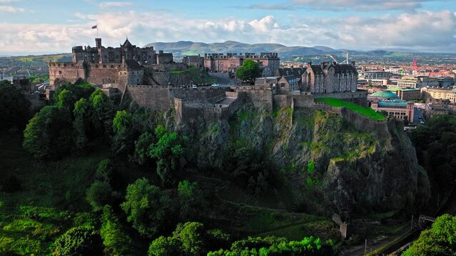 Aerial view of Edinburgh Castle with green gardens in Scotland. Historic castle and barracks housing the Crown Jewels and National War Museum of Scotland stands on Castle Rock.
