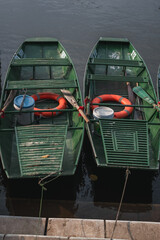 Fototapeta na wymiar Two green metal boats on the edge of a lake in Tam Coc, Vietnam