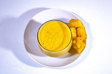 one mini glass cup, filled with pineapple juice and topped with a white plastic plate decorated with pineapple cubes on the side