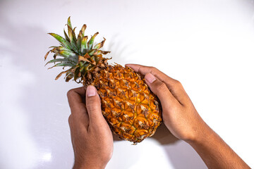 one fresh yellow pineapple, held in both hands carefully