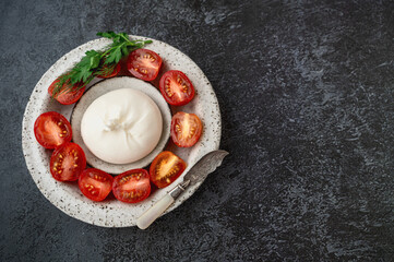 burrata with tomatoes. Caprese salad with tomatoes, burrata cheese and herbs. Soft cheese in a...