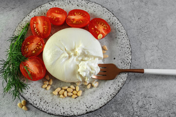 burrata with tomatoes. Caprese salad with tomatoes, burrata cheese and pine nuts. Cutaway soft...