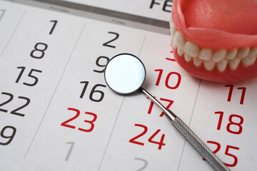 Dentist appointment calendar page and dentures model with mirror dental, close-up.