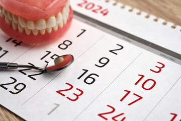 Dentist appointment calendar page and dentures model with mirror dental, close-up. - obrazy, fototapety, plakaty