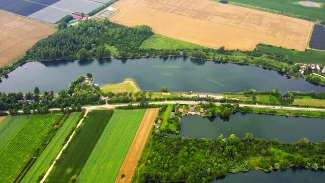 Aerial footage of vibrant green and gold fields surrounding lakes in summer
